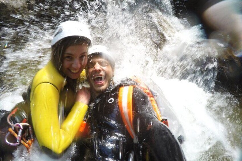 Two people in yellow jackets and helmets near a waterfall. 2