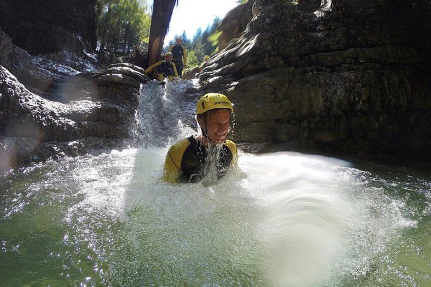 A person in a yellow helmet and life jacket in a river, with water splashing around. 2