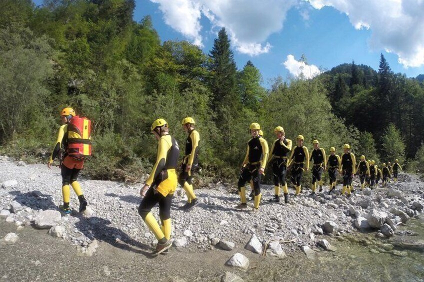 A group of people in yellow and black uniforms walking on a rocky path surrounded by trees. 4