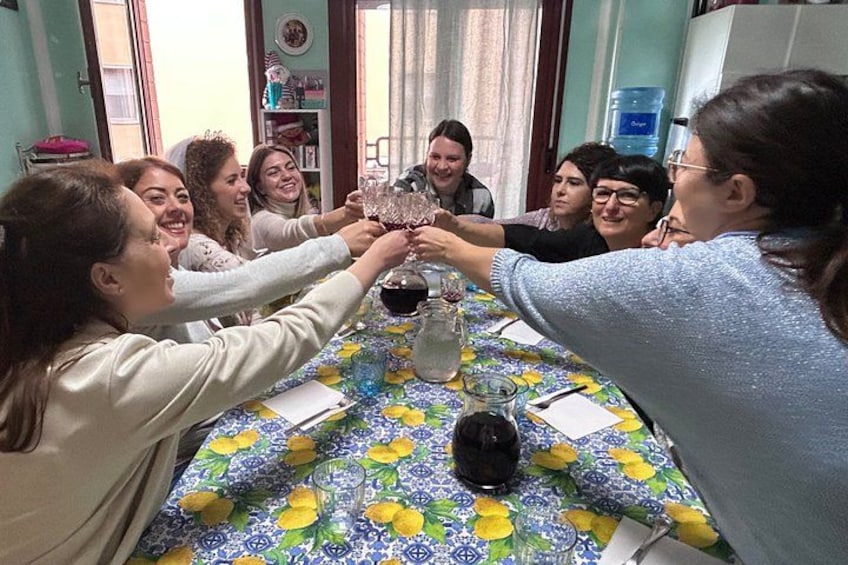 Un grupo de personas brindando con copas en una mesa con mantel floral. 1