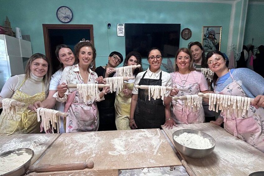 A group of people making pasta in a kitchen. 1
