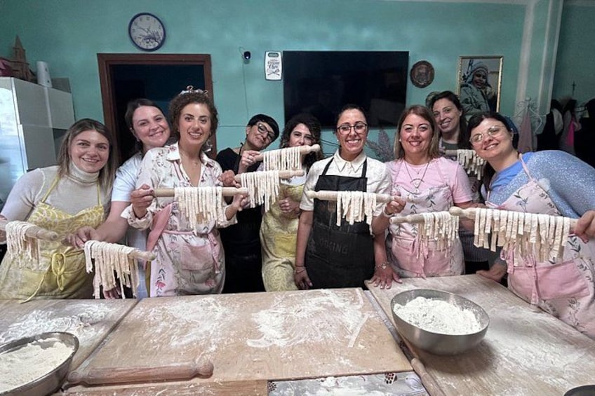 Un grupo de personas en una cocina sosteniendo pasta. 3
