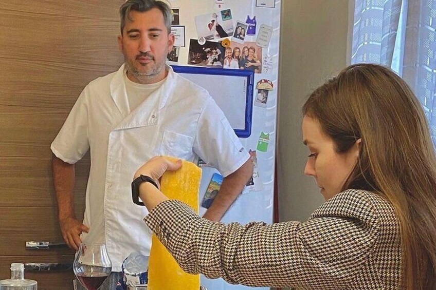 Una persona con delantal de chef blanco sosteniendo una esponja amarilla, de pie junto a otra persona con camisa a cuadros. 3