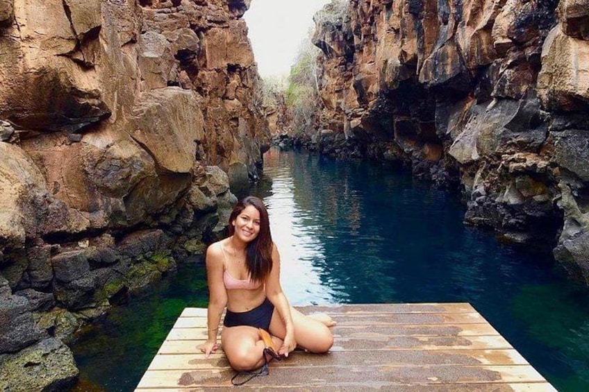 A person sitting on a wooden dock by a river with rocky cliffs. 5