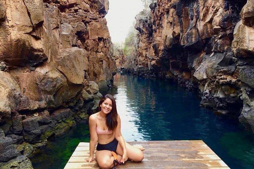 A person sitting on a wooden dock by a river with rocky cliffs. 2