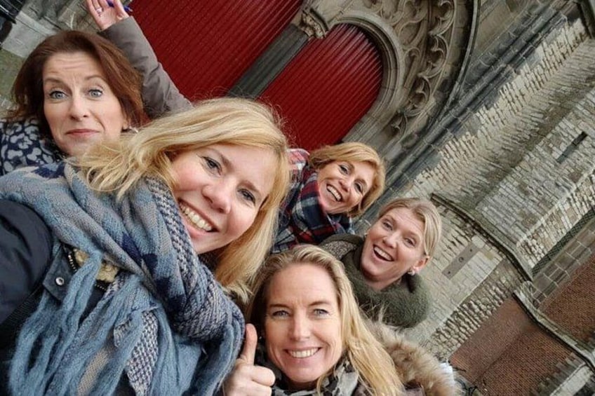 Eine Gruppe von Personen macht ein Selfie vor einem Gebäude mit aufwendiger Architektur. 2
