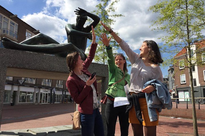 Trois personnes prennent une photo devant une sculpture, dans un environnement urbain. 2