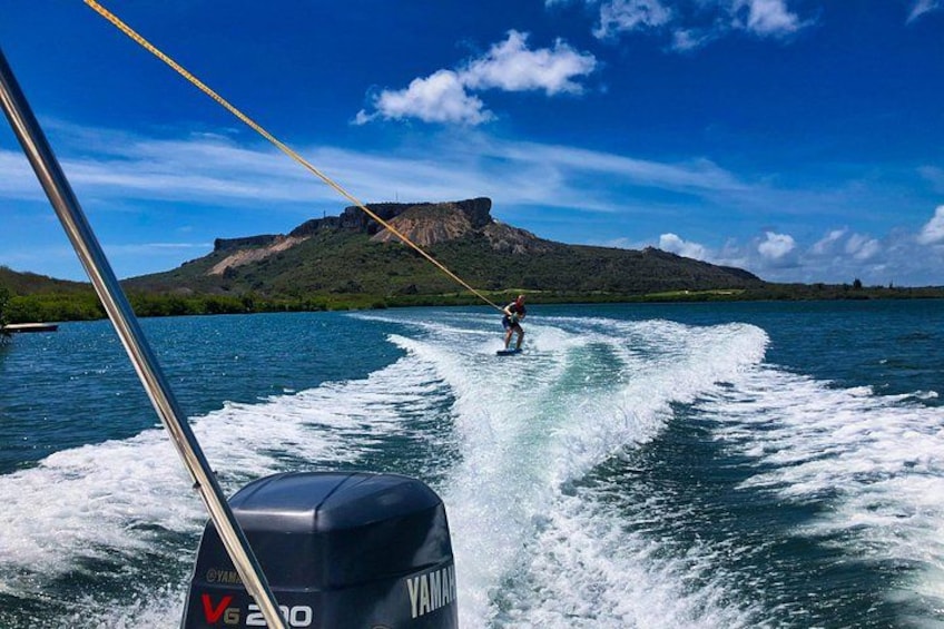 A wakeboarder on a body of water with mountains in the background. 1