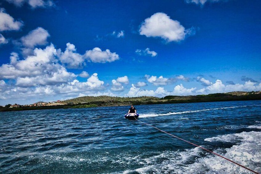 A person wakeboarding on a body of water with a rope, surrounded by a clear sky and distant land. 3