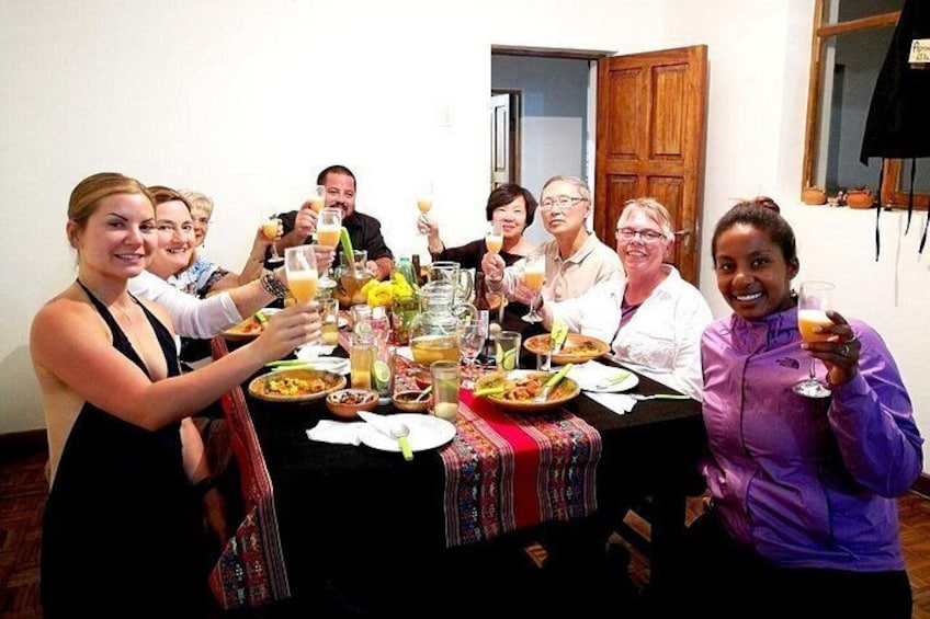 A group of people sitting around a table with food and drinks, in a room with wooden doors and a window. 3