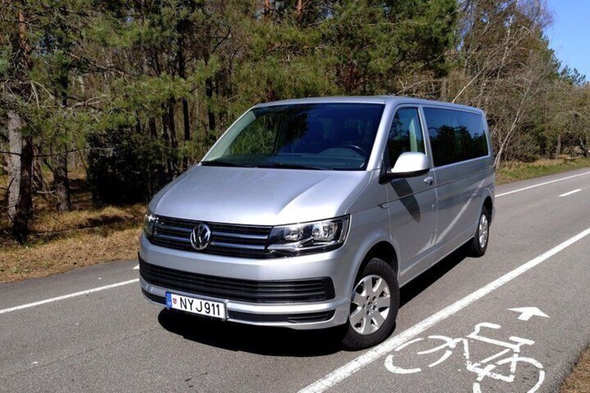 A silver Volkswagen van parked on a road with a bicycle lane. 3