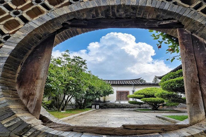 A traditional Korean courtyard with a wooden archway, a tiled floor, and a building with a tiled roof. 3