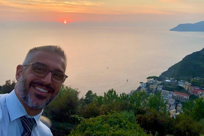 A coastal landscape with a sunset, a person in a white shirt and tie, and buildings along the coastline. 2