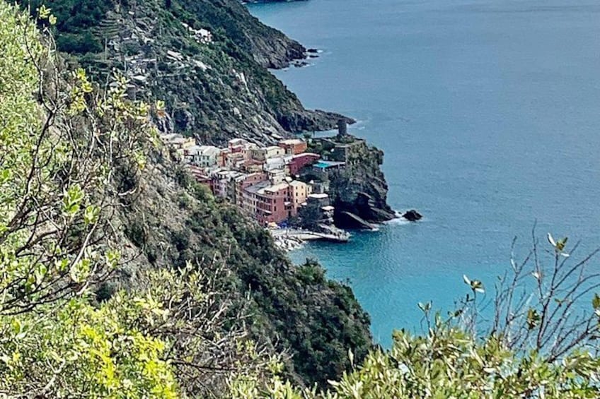 A coastal town with buildings on a cliff, surrounded by greenery and the sea. 4