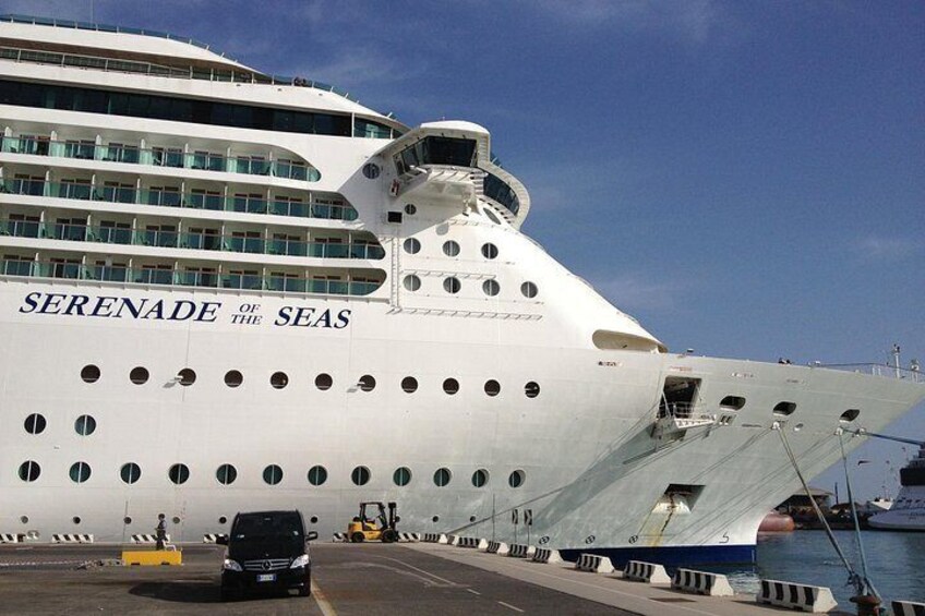A large cruise ship named 'Serenade of the Seas' docked at a port with a vehicle and a forklift nearby. 2