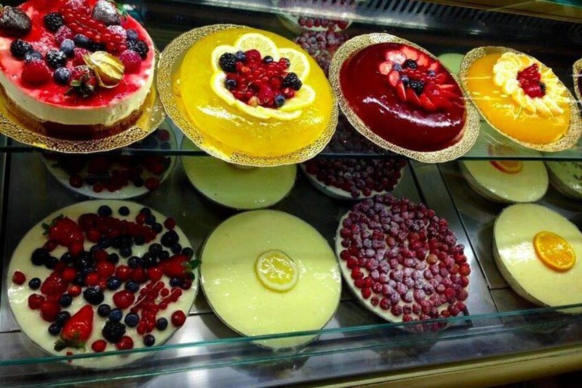 A variety of fruit-topped desserts in a display case. 1