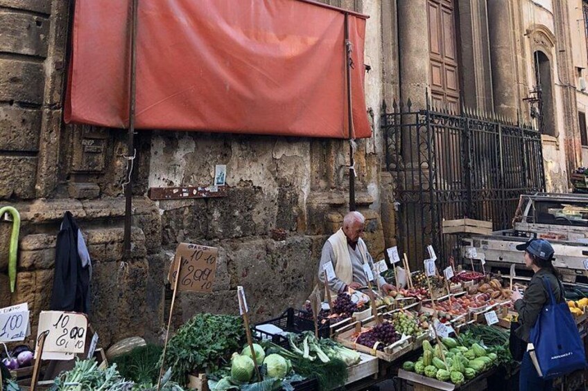 A street market with fresh produce and a red awning. 2