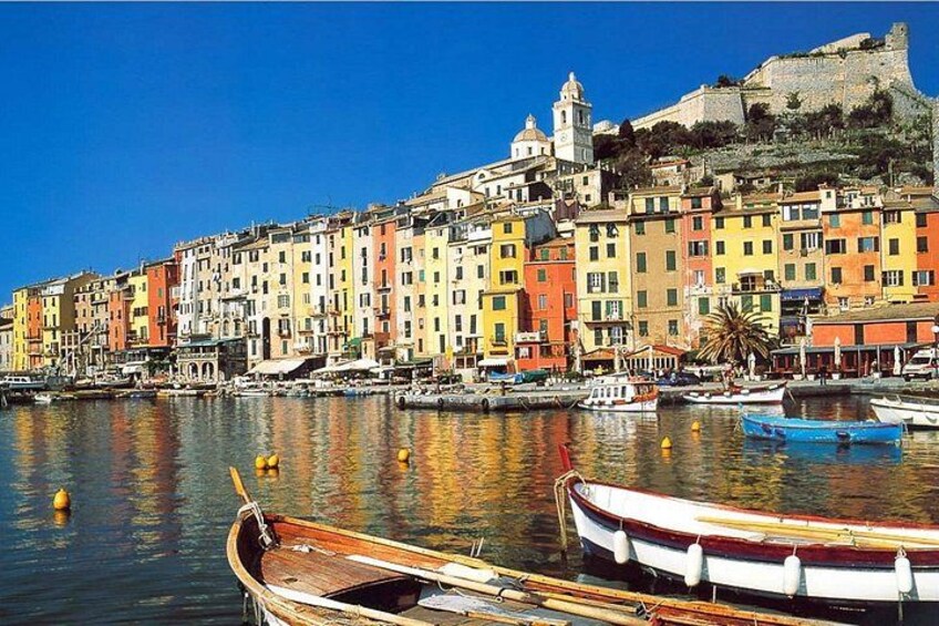 Una cittadina costiera con edifici colorati, un forte storico e barche nell'acqua. 1
