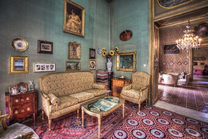 Una habitación de estilo antiguo con un tapete estampado, un sofá, una silla y varias fotos enmarcadas en la pared. 3