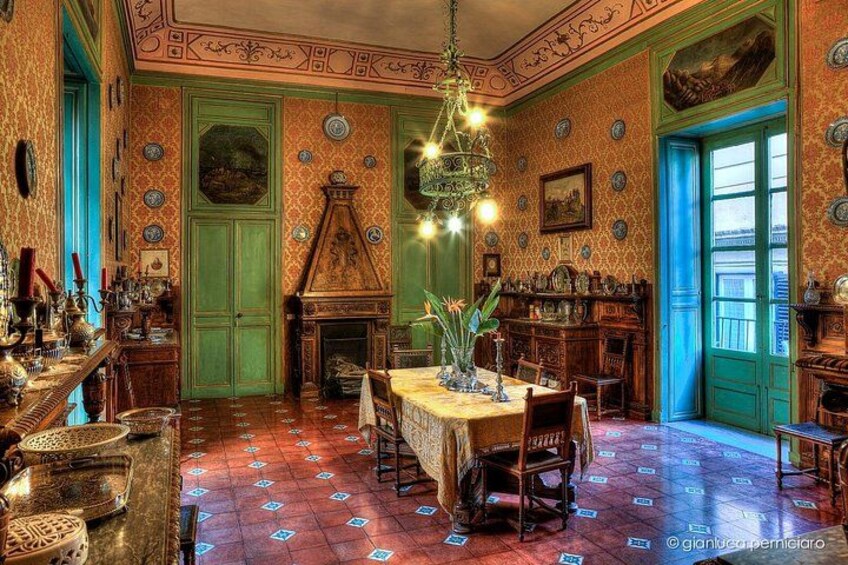 A room with a green door, a chandelier, and patterned wallpaper. 2