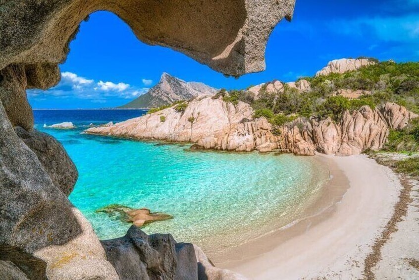 Una playa con aguas turquesas cristalinas, acantilados rocosos y un cielo despejado. 5