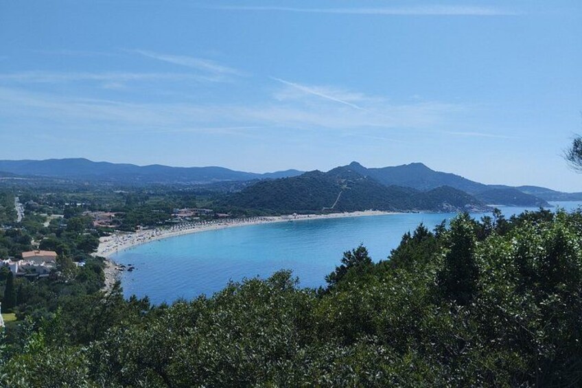 Un paisaje costero con mar azul cristalino, una playa arenosa y montañas al fondo. 2
