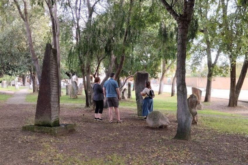 A group of people walking in a cemetery with trees and tombstones. 4
