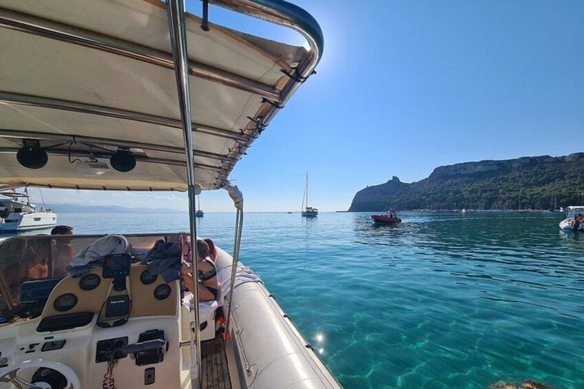 Ein Boot auf klarem türkisblauem Wasser vor einer gebirgigen Küstenlinie. 2