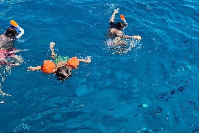 Tres personas nadando en una piscina con flotadores anaranjados. 5