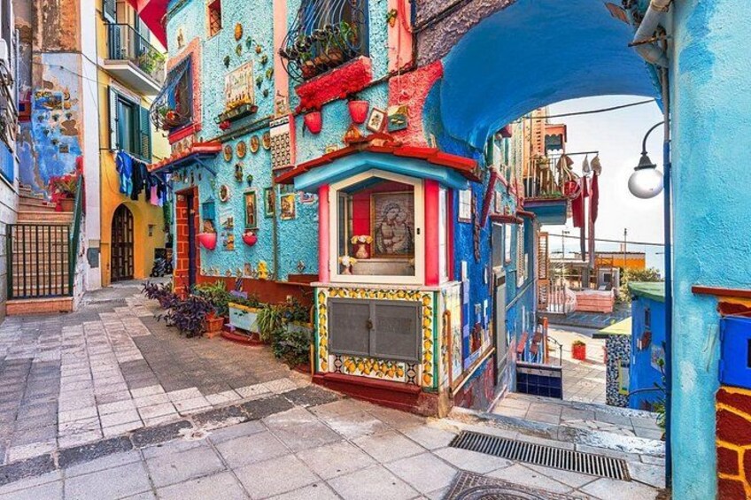 A colorful street with vibrant buildings, a narrow alley, and a blue archway. 4