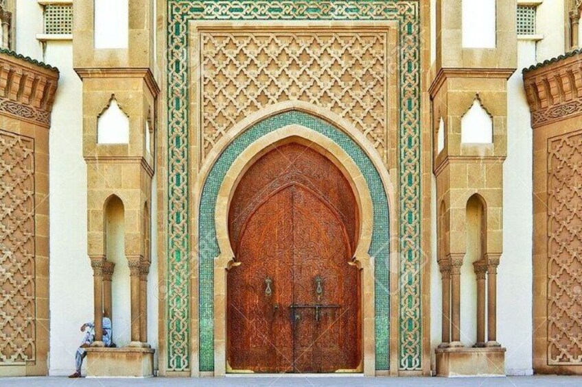 A large wooden door with intricate geometric patterns, flanked by tall columns and arches. 3