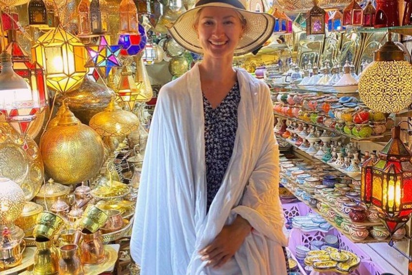 A person in a market with various colorful lanterns and glassware. 4