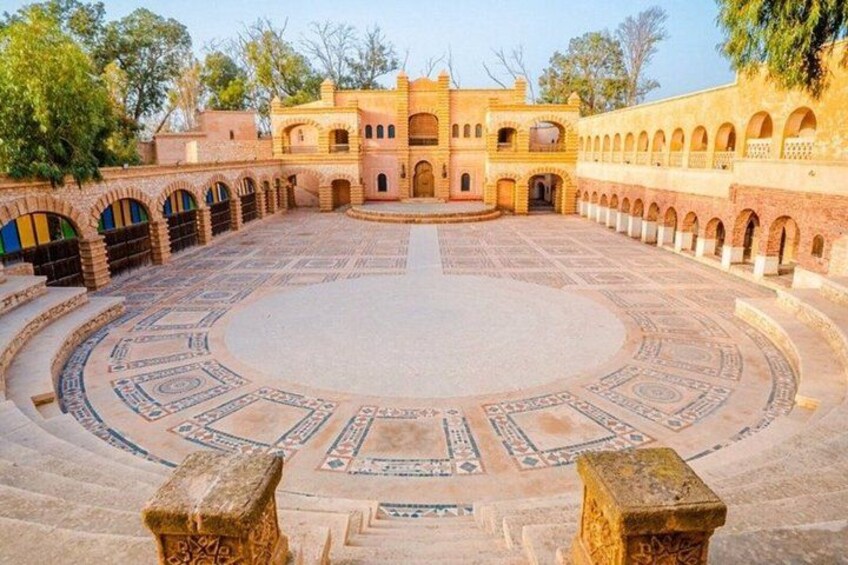 A courtyard with a circular patterned floor, arched walkways, and a central building with a dome. 2