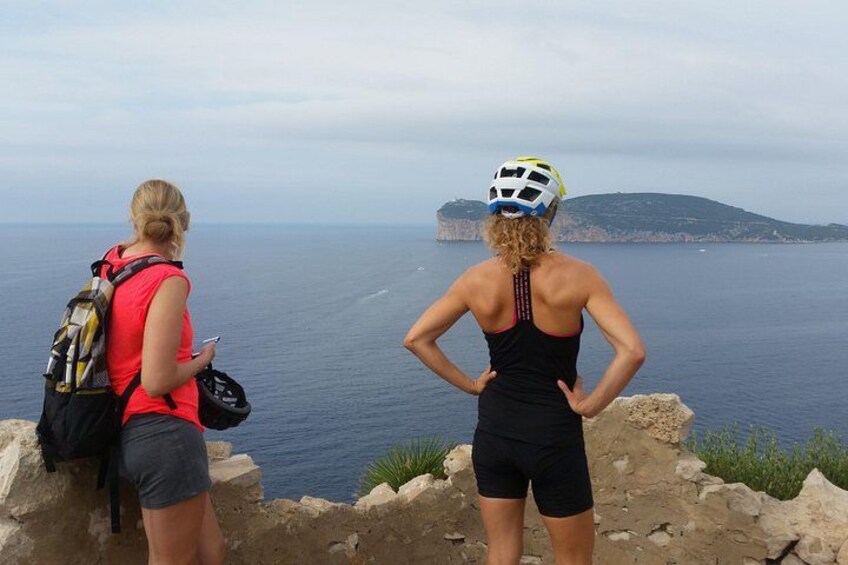 Dos personas sobre un saliente rocoso con vistas a una masa de agua y una isla distante. 5