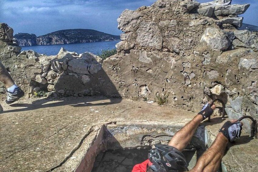 Una persona recostada sobre una superficie rocosa, con vista a un paisaje costero y un cuerpo de agua al fondo. 3