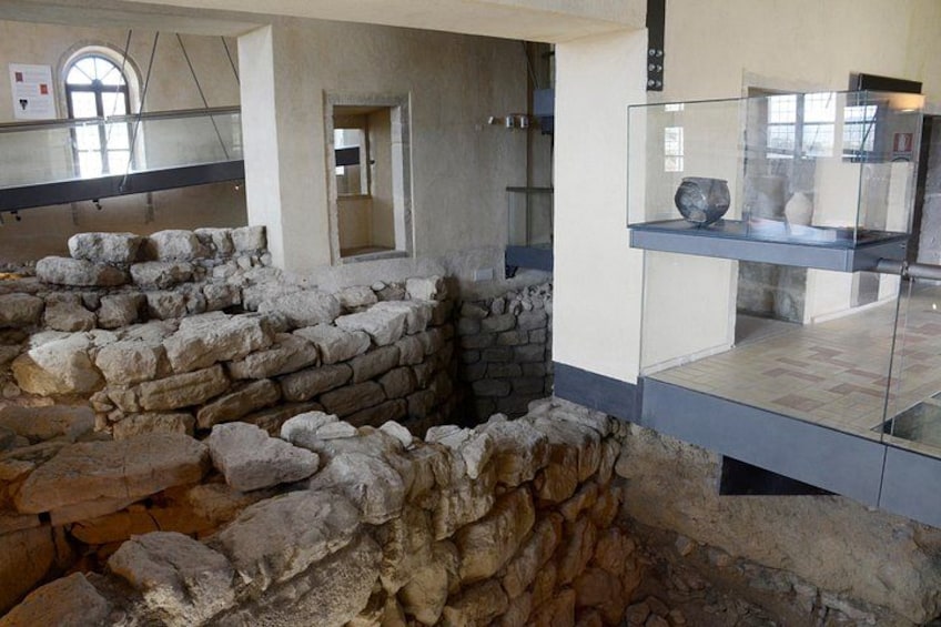 An archaeological site with stone walls and a glass display case. 2