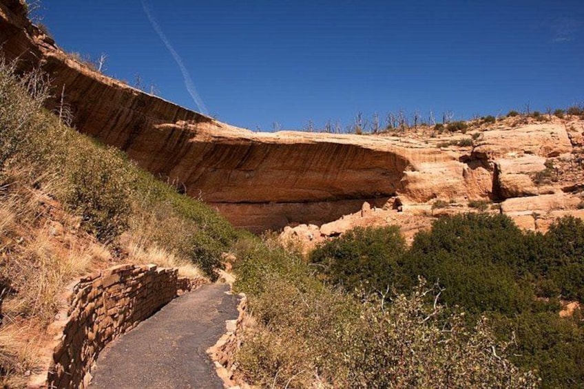 Un cañón con un sendero estrecho, acantilados rocosos y vegetación escasa. 3