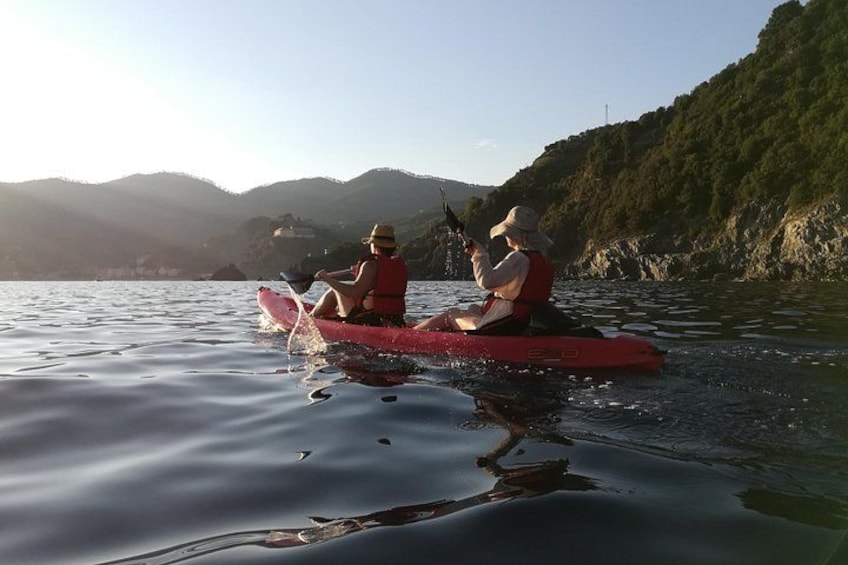 Two people kayaking on a calm river with mountains in the background. 5