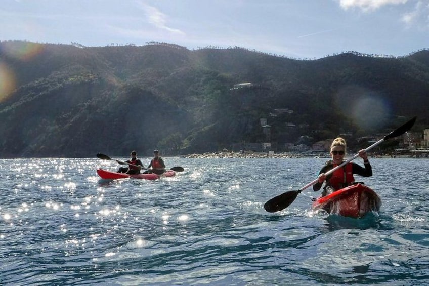 Two people kayaking on a calm body of water with a mountainous landscape in the background. 2