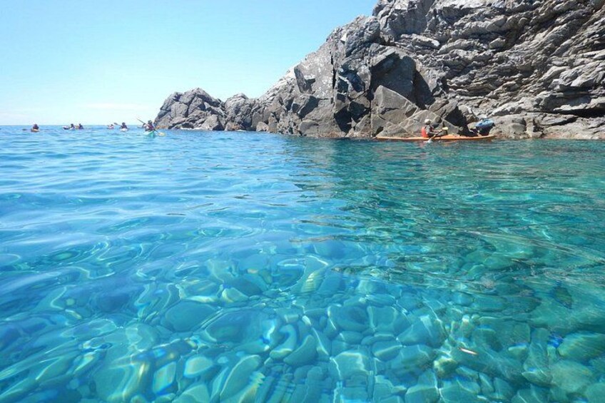Clear blue water, rocky coastline, and kayaks. 4