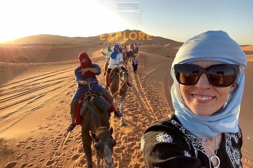 A desert landscape with people riding camels. 2