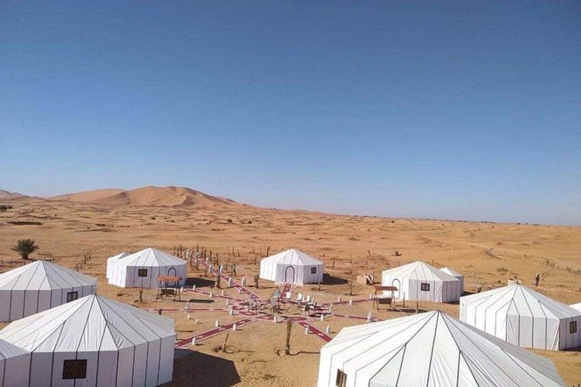 Yurts in a desert landscape with sand dunes in the background. 5