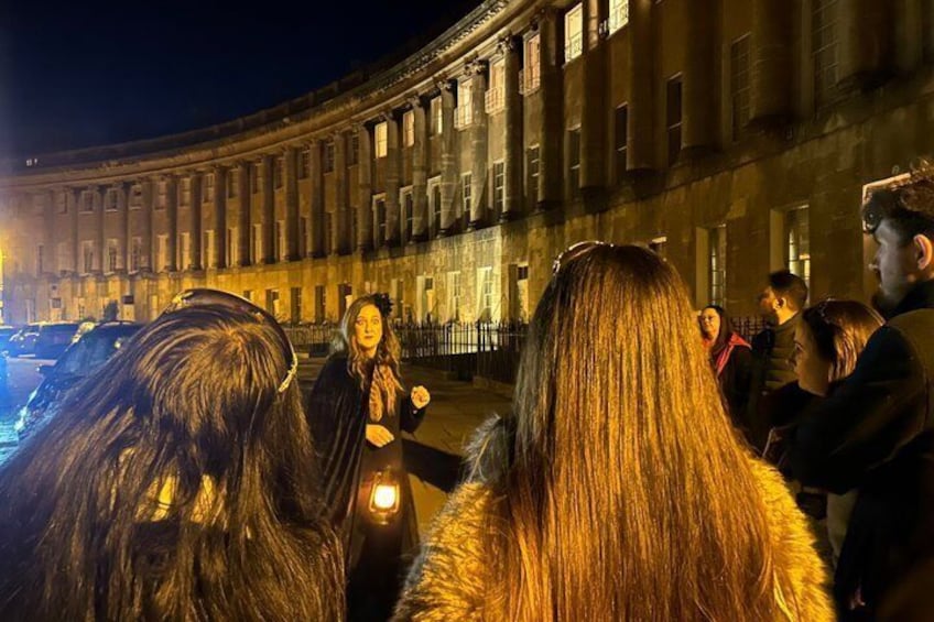 A group of people standing in front of a historic building with classical architecture at night. 2