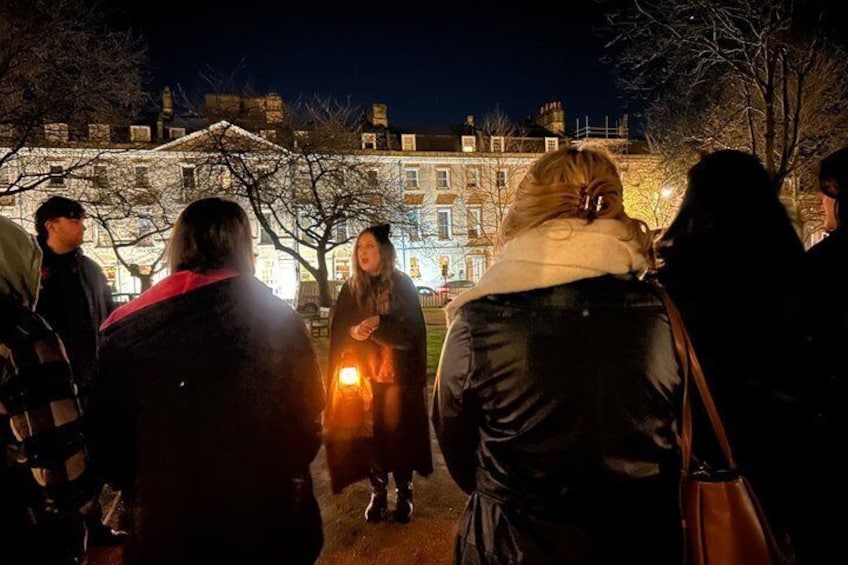 A group of people standing outdoors at night with a building in the background. 3