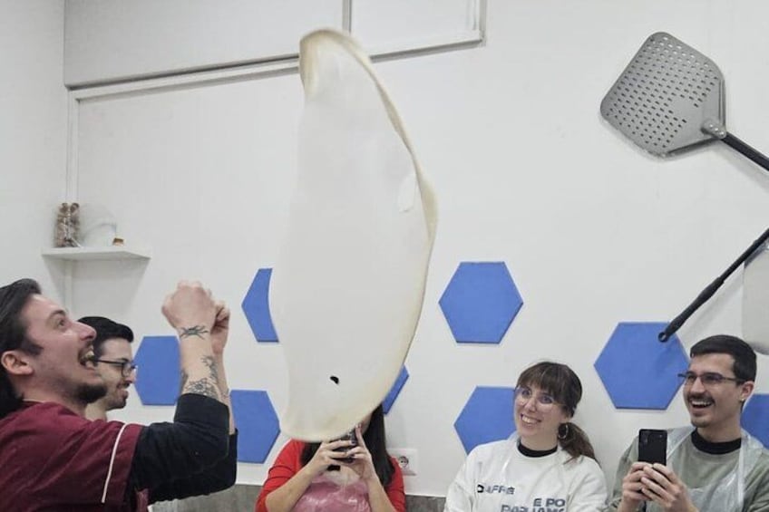 A group of people holding a large white object in a room with blue hexagonal patterns on the wall. 1