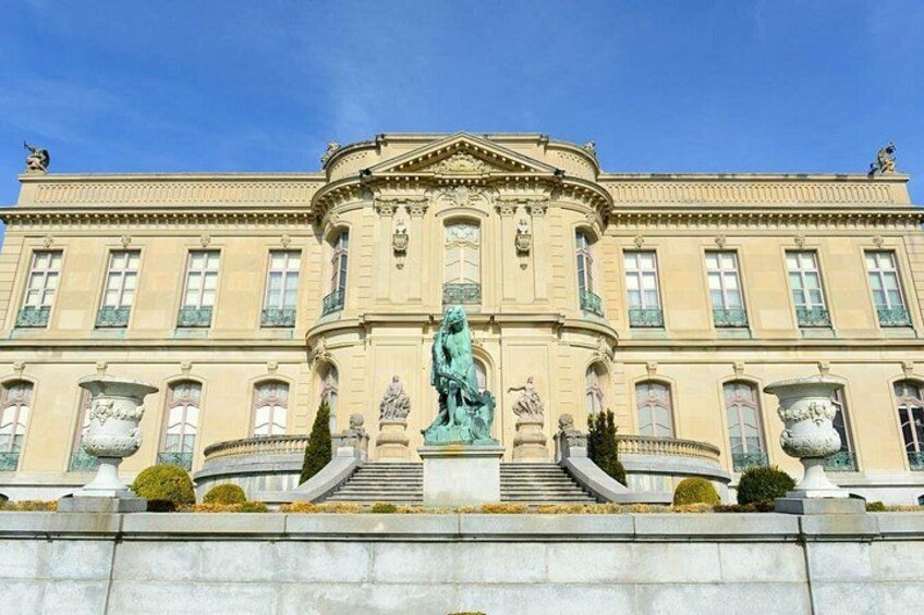 A classical building with a central statue, large windows, and a symmetrical facade. 5