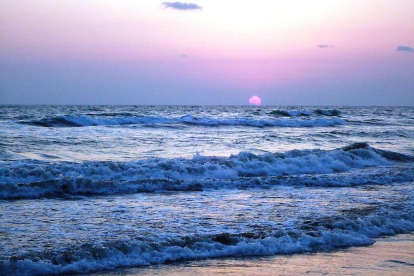 A sunset over the ocean with waves crashing onto the shore. 1