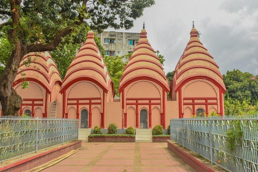 A temple with three domed structures, surrounded by a metal fence and greenery. 2