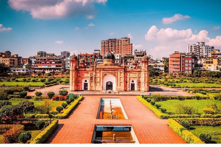 A historic building with a central courtyard, surrounded by well-maintained gardens and modern buildings in the background. 1