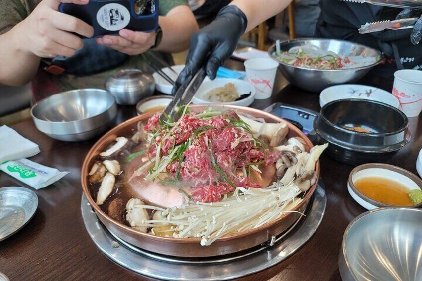 Una olla caliente con ingredientes variados como setas, carne y verduras. 2